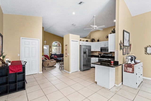 kitchen with light tile patterned floors, a peninsula, visible vents, appliances with stainless steel finishes, and dark countertops