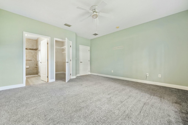 unfurnished bedroom with baseboards, carpet flooring, visible vents, and a walk in closet