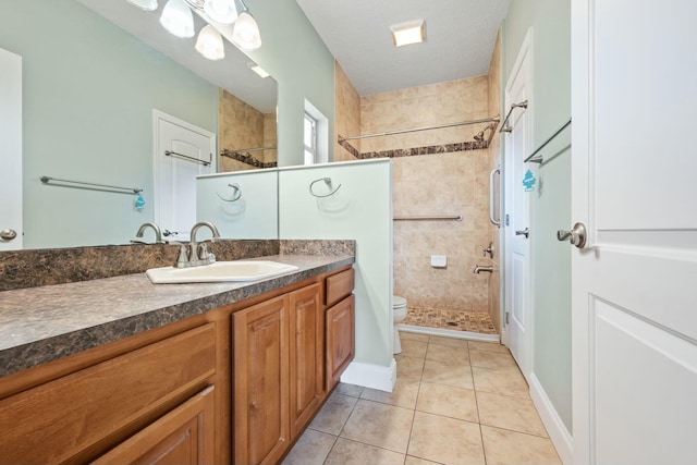 full bath with toilet, tile patterned flooring, a tile shower, and vanity