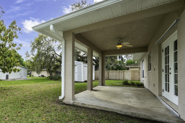 view of patio / terrace featuring ceiling fan, fence, a storage unit, and an outbuilding