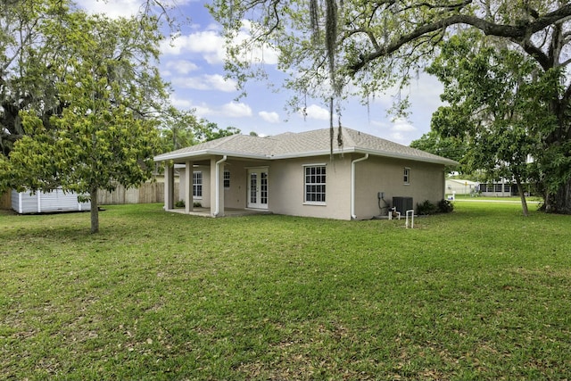 back of house with french doors, stucco siding, a lawn, central AC unit, and fence