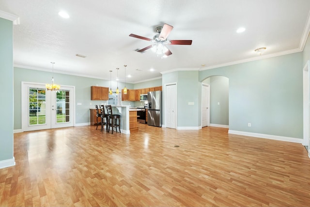 unfurnished living room with baseboards, arched walkways, ornamental molding, light wood-type flooring, and ceiling fan with notable chandelier