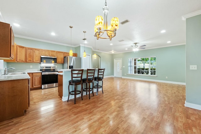 kitchen with stainless steel appliances, a sink, visible vents, a center island, and light wood finished floors