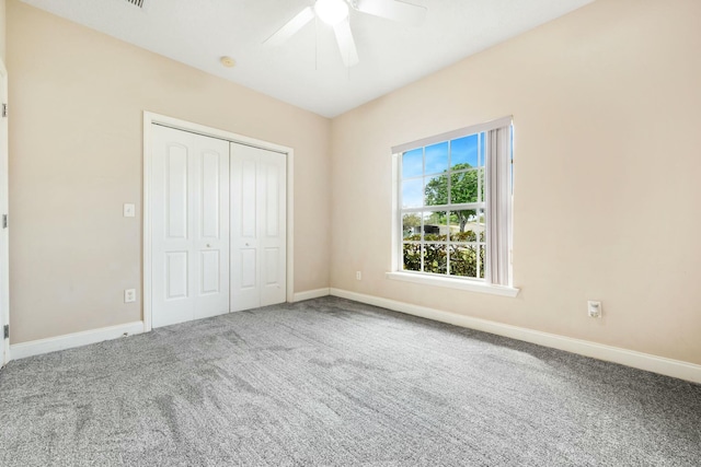 unfurnished bedroom featuring carpet floors, a closet, baseboards, and a ceiling fan