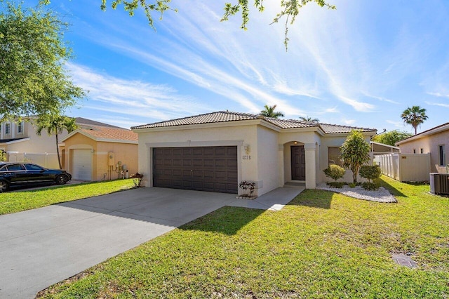 mediterranean / spanish-style home featuring stucco siding, a front lawn, driveway, fence, and a garage