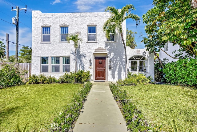 view of front of house featuring stucco siding, a front yard, and fence