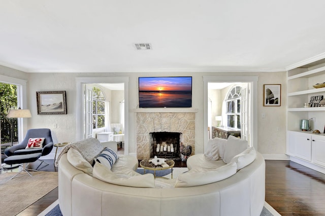 living room with dark wood-style floors, visible vents, a fireplace, and a wealth of natural light