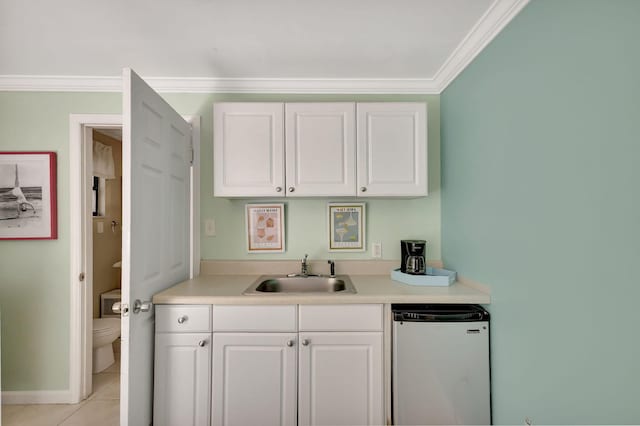 kitchen with fridge, white cabinets, light tile patterned floors, and a sink