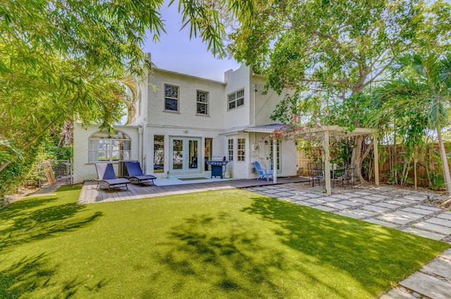 back of house with french doors, a yard, stucco siding, and fence