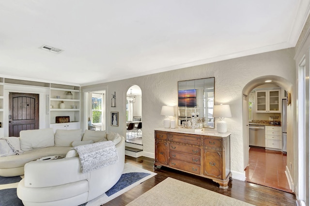 living area featuring baseboards, ornamental molding, a textured wall, arched walkways, and dark wood-style flooring