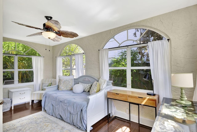 bedroom featuring a ceiling fan, wood finished floors, and a textured wall