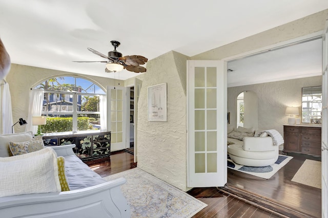 bedroom featuring arched walkways, hardwood / wood-style flooring, ceiling fan, and a textured wall