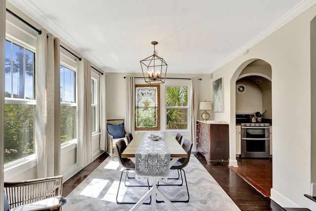 535 28th St, West Palm Beach, FL 33407 - dining space featuring dark wood-style flooring, crown molding, a chandelier, and arched walkways