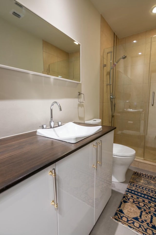 bathroom featuring visible vents, a stall shower, toilet, and vanity