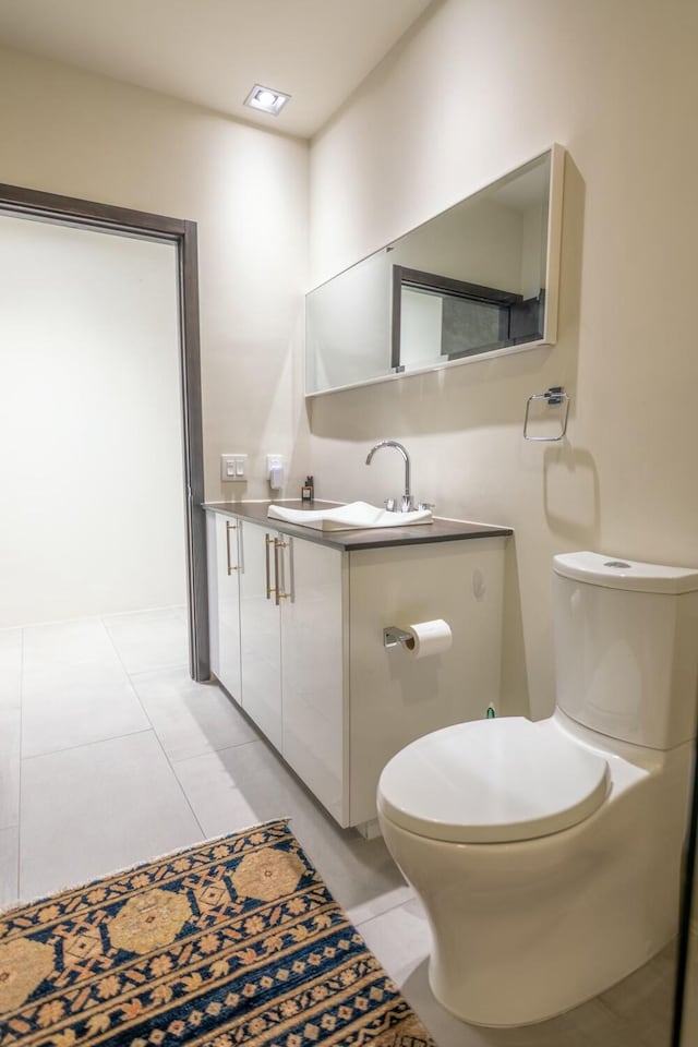 half bath featuring tile patterned flooring, toilet, and vanity