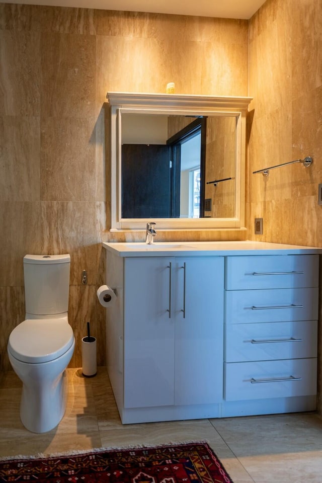 bathroom featuring tile walls, tile patterned flooring, toilet, and vanity