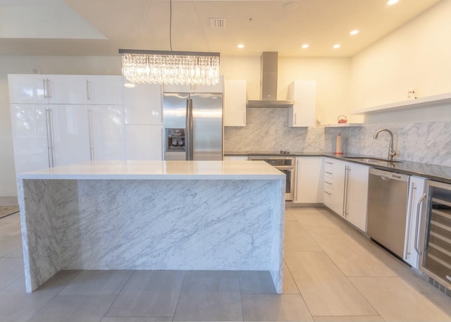 kitchen featuring wine cooler, appliances with stainless steel finishes, white cabinets, wall chimney exhaust hood, and a sink