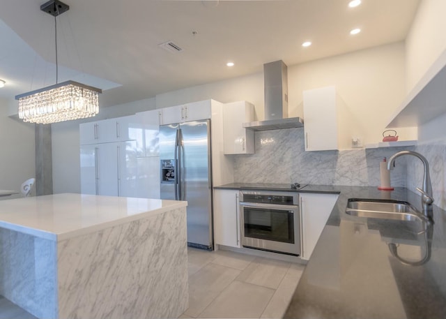 kitchen with visible vents, a sink, stainless steel appliances, wall chimney exhaust hood, and white cabinets