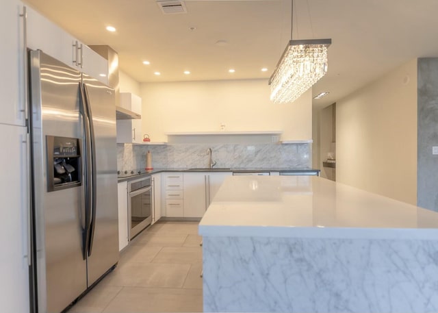 kitchen featuring visible vents, a kitchen island, light tile patterned floors, appliances with stainless steel finishes, and a sink