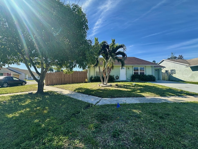 exterior space with driveway, fence, and a front lawn