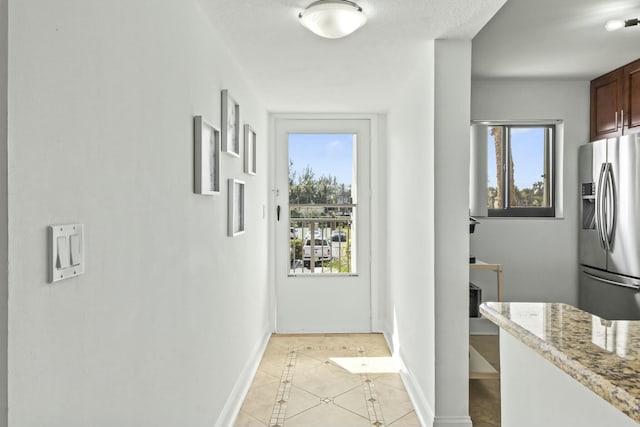 entryway featuring a healthy amount of sunlight, light tile patterned floors, and baseboards