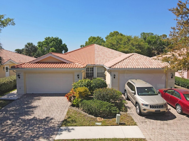 mediterranean / spanish-style home with driveway, an attached garage, and a tile roof