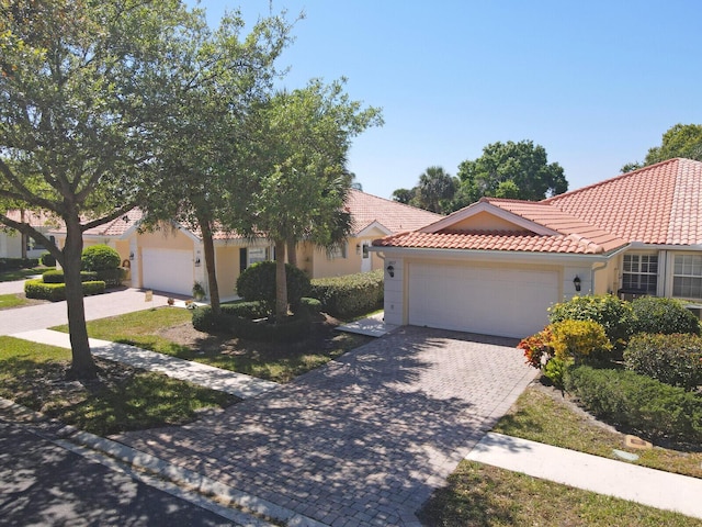 view of front of home with a garage, decorative driveway, stucco siding, and a tile roof