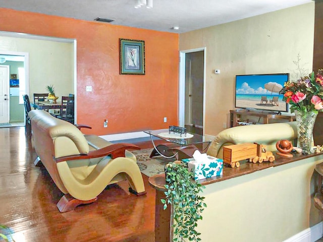 living area featuring wood finished floors, visible vents, and baseboards