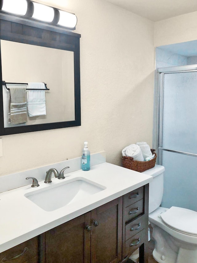 bathroom featuring toilet, a shower stall, and vanity