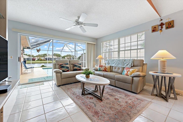 living area with a textured ceiling, light tile patterned floors, a sunroom, and a ceiling fan