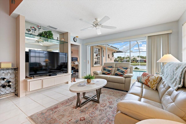 living room with light tile patterned floors, visible vents, a ceiling fan, a sunroom, and a textured ceiling