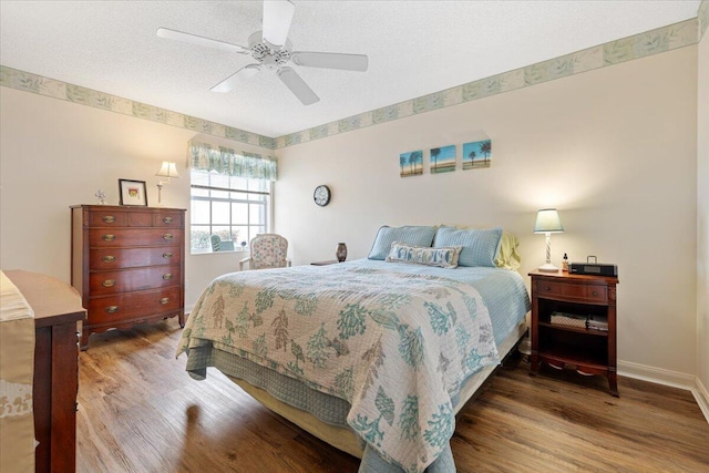 bedroom with ceiling fan, a textured ceiling, baseboards, and wood finished floors