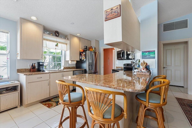 kitchen with stainless steel appliances, visible vents, a peninsula, and tasteful backsplash