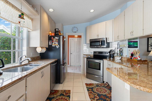 kitchen with light tile patterned floors, decorative backsplash, a peninsula, stainless steel appliances, and a sink