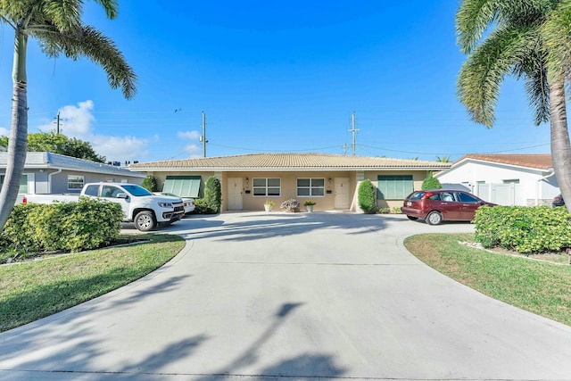 ranch-style house with concrete driveway, a tiled roof, and stucco siding