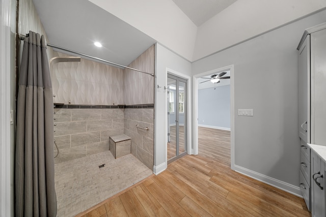 bathroom featuring a tile shower, baseboards, and wood-type flooring