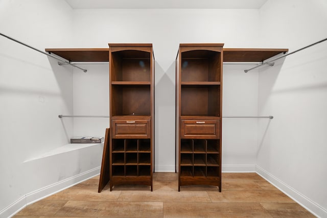 walk in closet with light wood-style floors