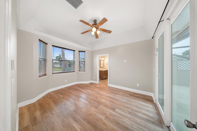 interior space with visible vents, a raised ceiling, light wood-style floors, and baseboards