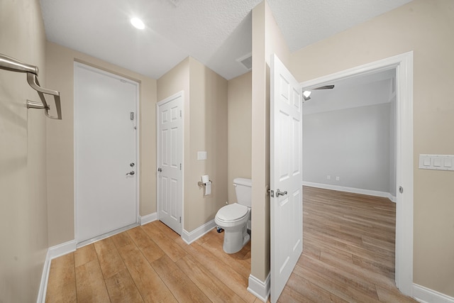 bathroom with toilet, wood finished floors, baseboards, and a textured ceiling