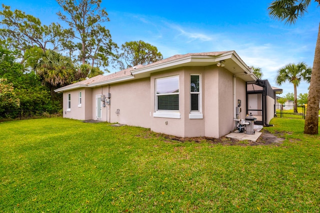 back of property featuring glass enclosure, fence, a yard, and stucco siding