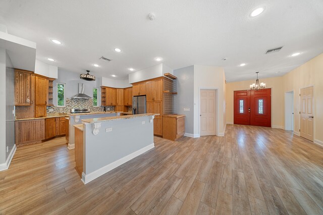 kitchen featuring visible vents, wall chimney exhaust hood, stainless steel refrigerator with ice dispenser, and open shelves