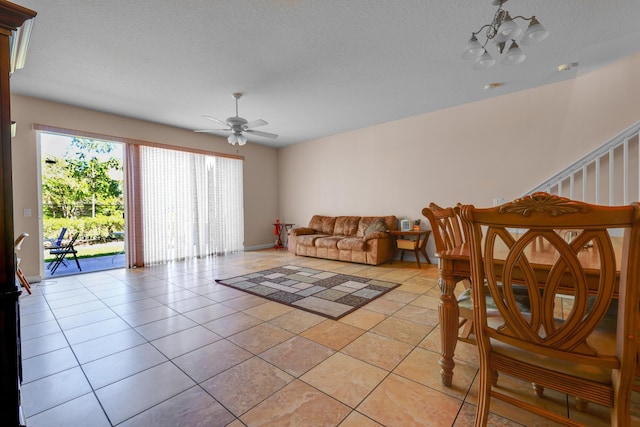 living area featuring ceiling fan with notable chandelier, a textured ceiling, and light tile patterned floors