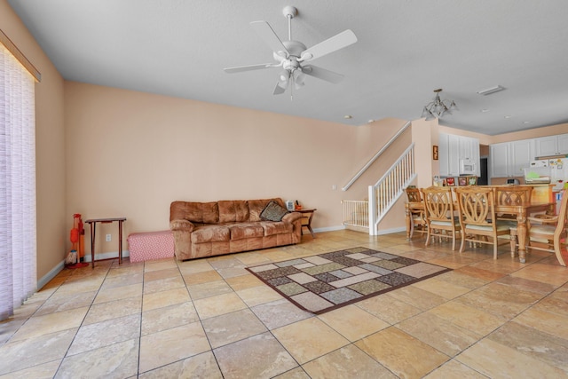 living room with stairs, light tile patterned flooring, a ceiling fan, and baseboards