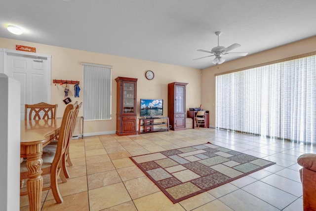 living room featuring ceiling fan, baseboards, and light tile patterned floors