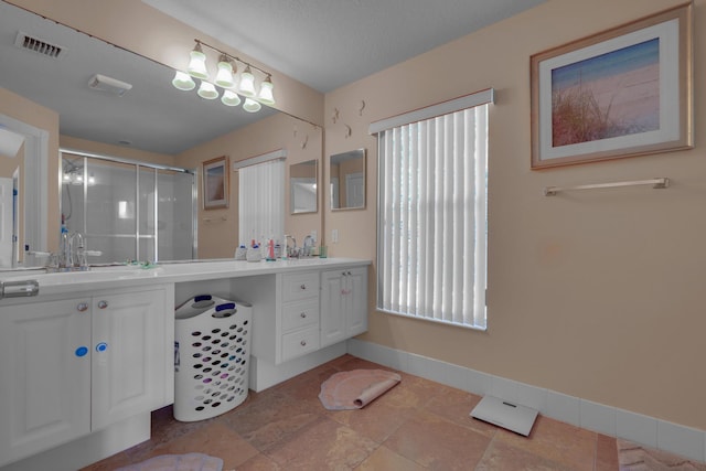 bathroom featuring double vanity, baseboards, visible vents, a shower stall, and a sink