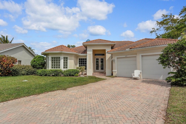 mediterranean / spanish home with french doors, decorative driveway, an attached garage, and a tile roof