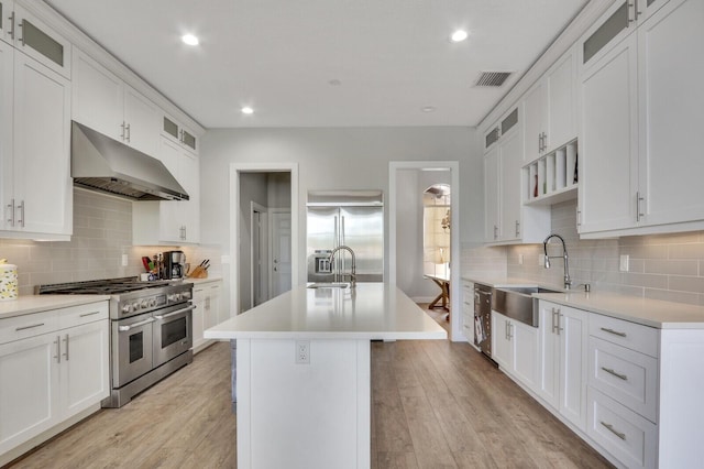 kitchen with visible vents, premium appliances, a sink, under cabinet range hood, and light wood-type flooring