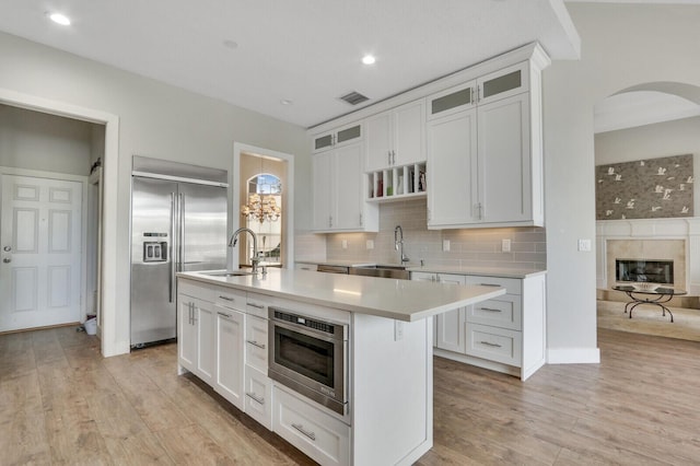 kitchen with stainless steel built in refrigerator, decorative backsplash, light countertops, and a sink