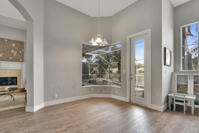 dining room with a high end fireplace, a chandelier, baseboards, and wood finished floors