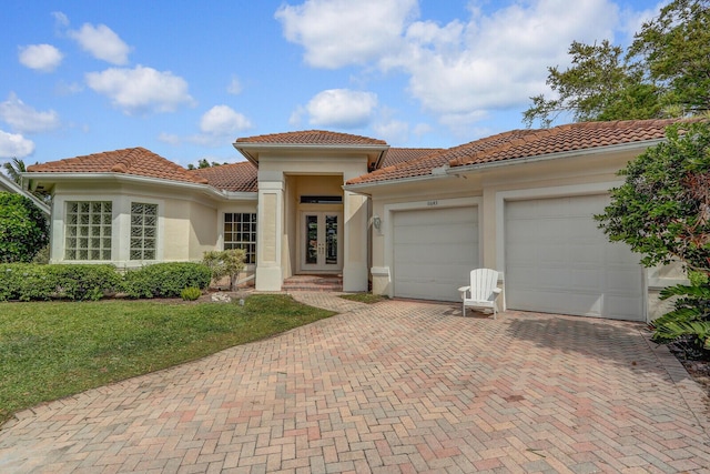 mediterranean / spanish-style house featuring stucco siding, french doors, a garage, a tiled roof, and decorative driveway